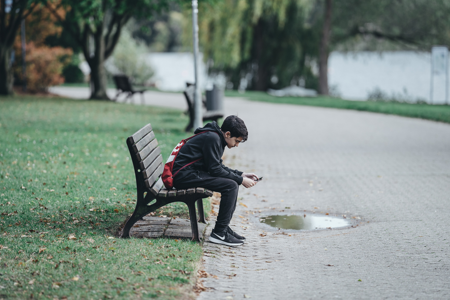 Teenage boy using smartphone on park bench